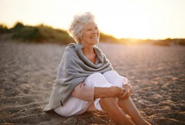 Cheerful Old Woman Sitting on sand